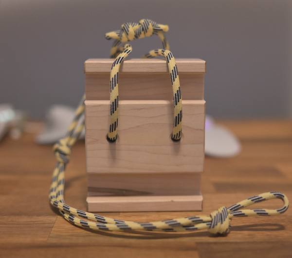 a finished crimp block made of maple with a paracord sling
